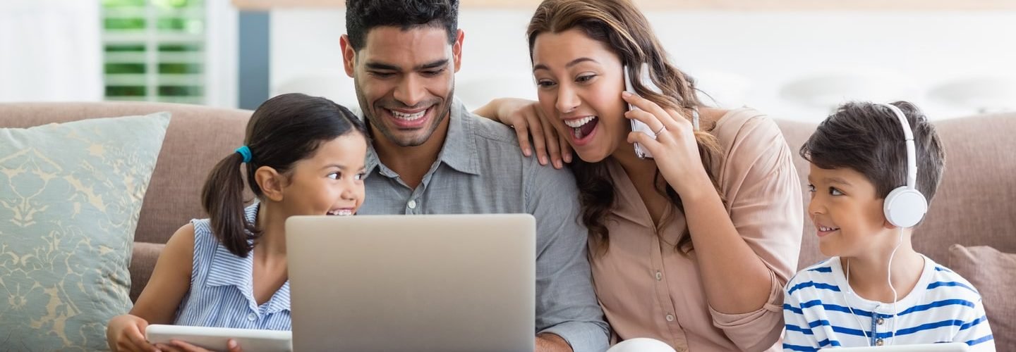 parents-kids-using-laptop-digital-tablet-living-room-min